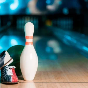 Bowling alley scene with a single pin and ball on the polished lane. A pair of bowling shoes, one red and one blue, rest beside the pin.